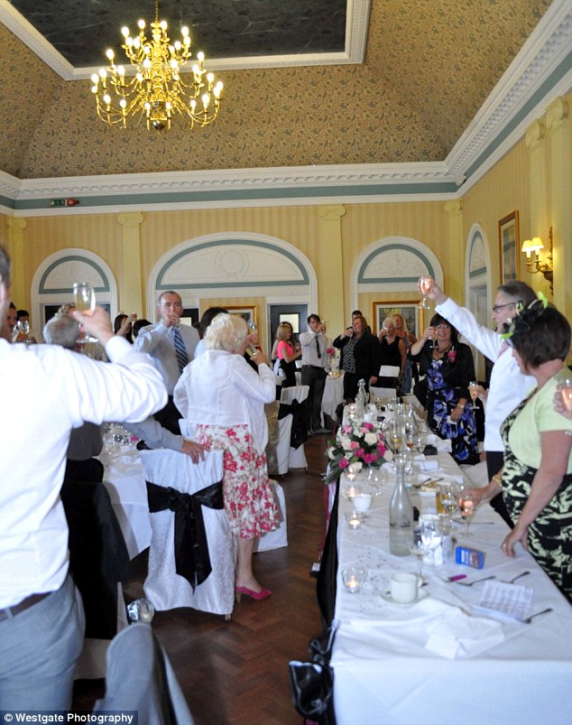 Cheers! The guests are photographed - largely from behind - raising their glasses to the happy couple, who are nowhere to be seen in this picture