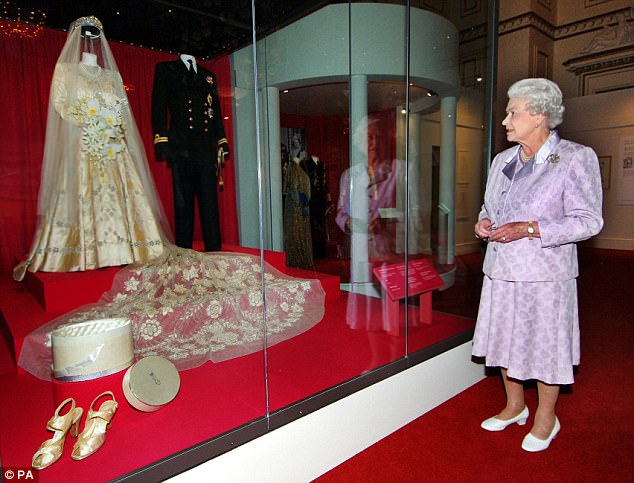 Queen Elizabeth II is pictured in 2007 looking at her 1947 wedding gown and 13-foot bridal trail designed by Norman Hartnell with the naval uniform worn by the Duke of Edinburgh