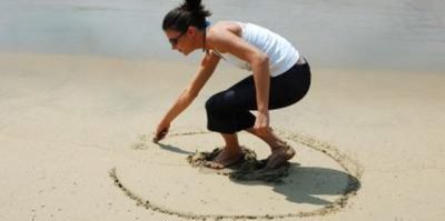 Девушка рисует круг на песке